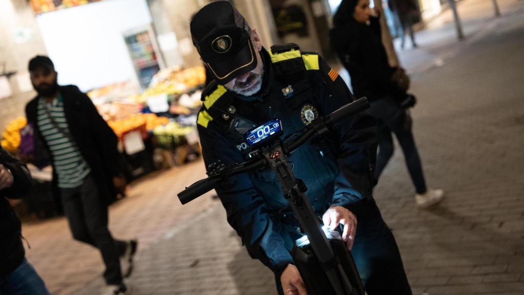 Un agente de la Guardia Urbana de Badalona revisando un patinete