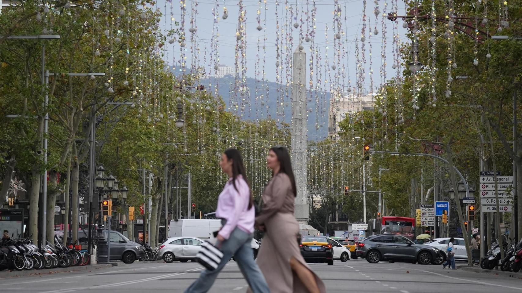 Dos personas pasean por paseo de Gracia bajo las luces de Navidad
