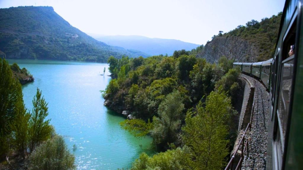 Un viajero se asoma a ver un lago en un tren