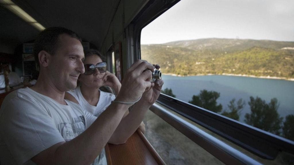 Una pareja fotografía un paisaje desde el tren