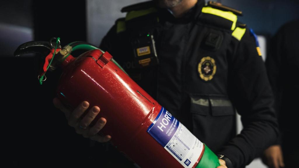 Un agent de la Guàrdia Urbana de Barcelona s'emporta un extintor d'un local