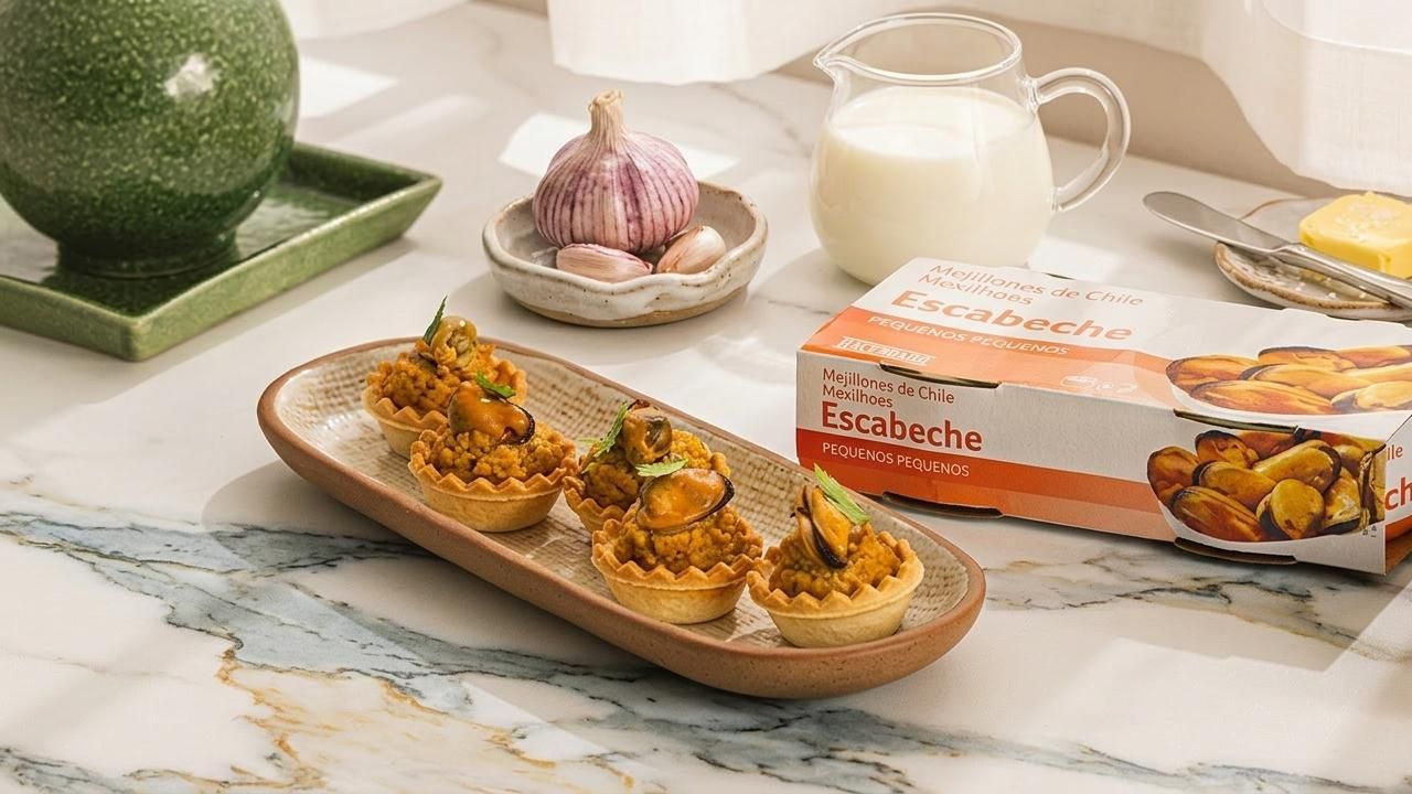 El plato de tartaletas con crema de mejillón con varios de los ingredientes que se necesitan para prepararlos: leche, ajo y mantequilla