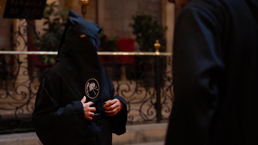 Una persona sin techo probándose una túnica para la procesión del Cristo de la Buena Muerte