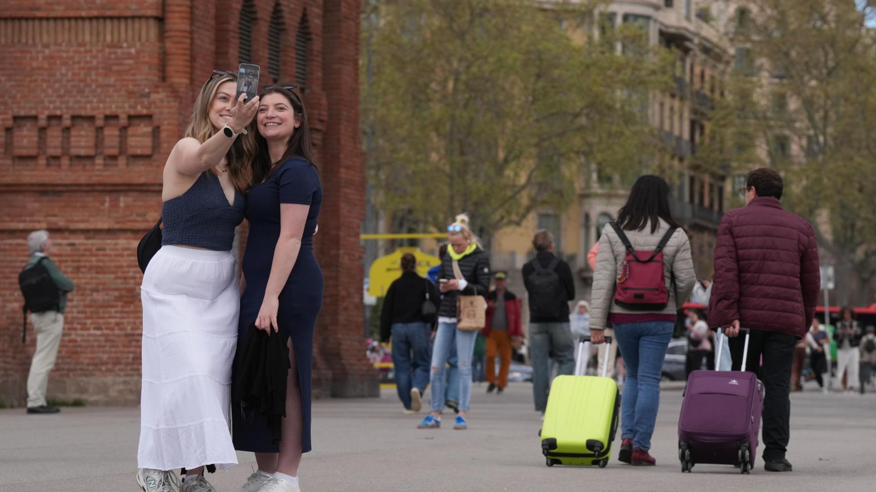 Dos turistas junto al Arc del Trionf de Barcelona haciéndose un selfie