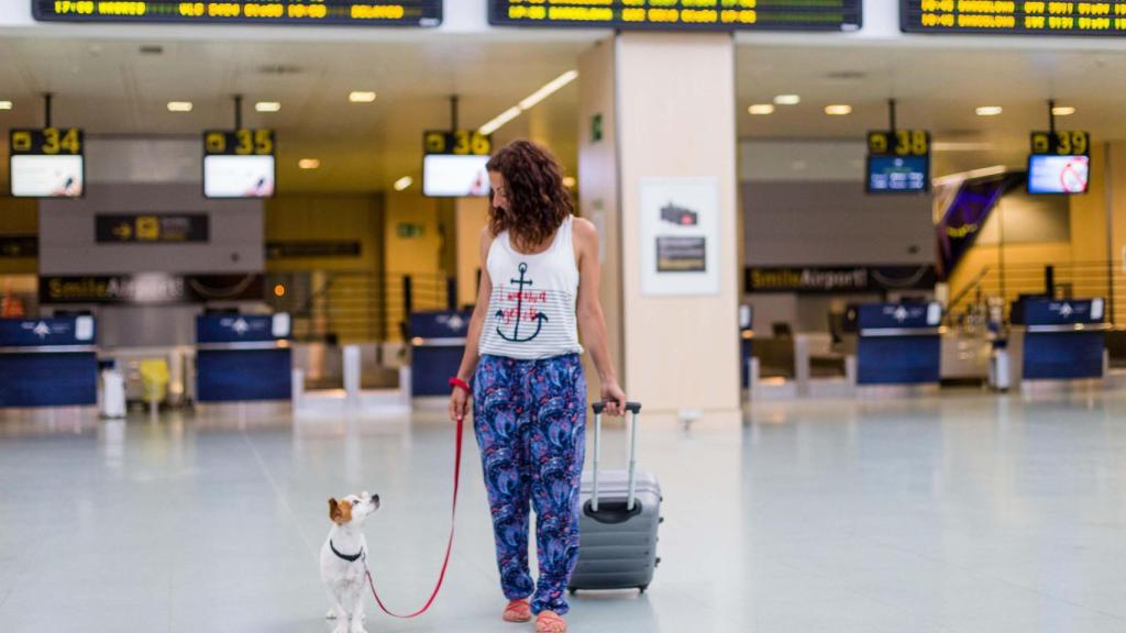 Un perro junto a su dueña en un aeropuerto en una imagen de archivo