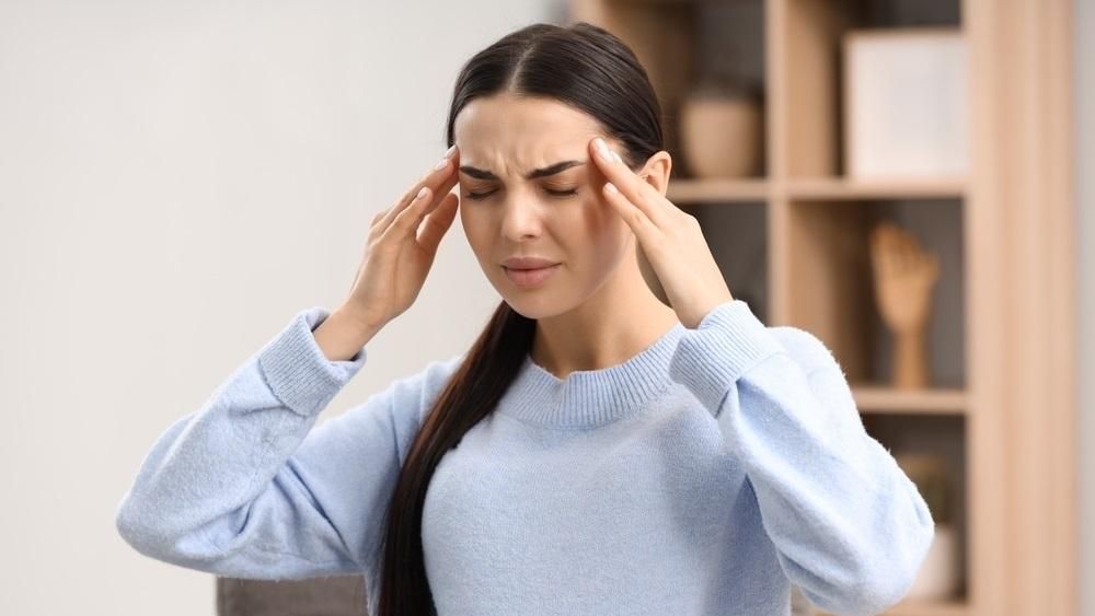 Una joven se aprieta las sienes a causa del dolor