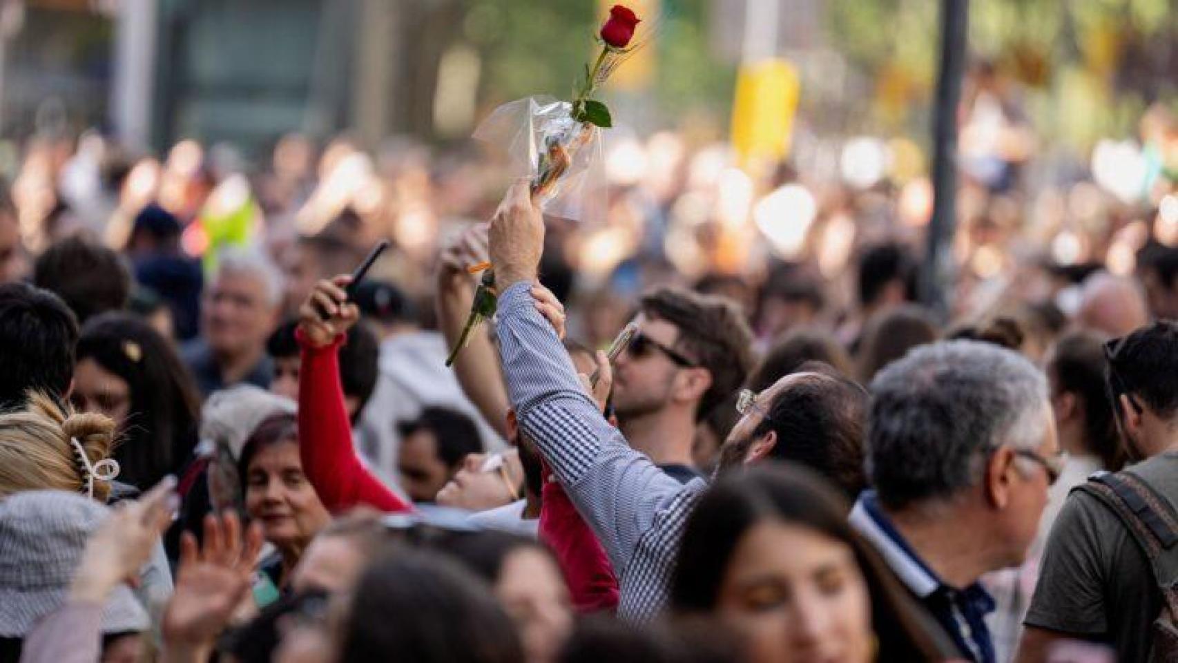 Un hombre alza una rosa frente a la Casa Batlló por Sant Jordi