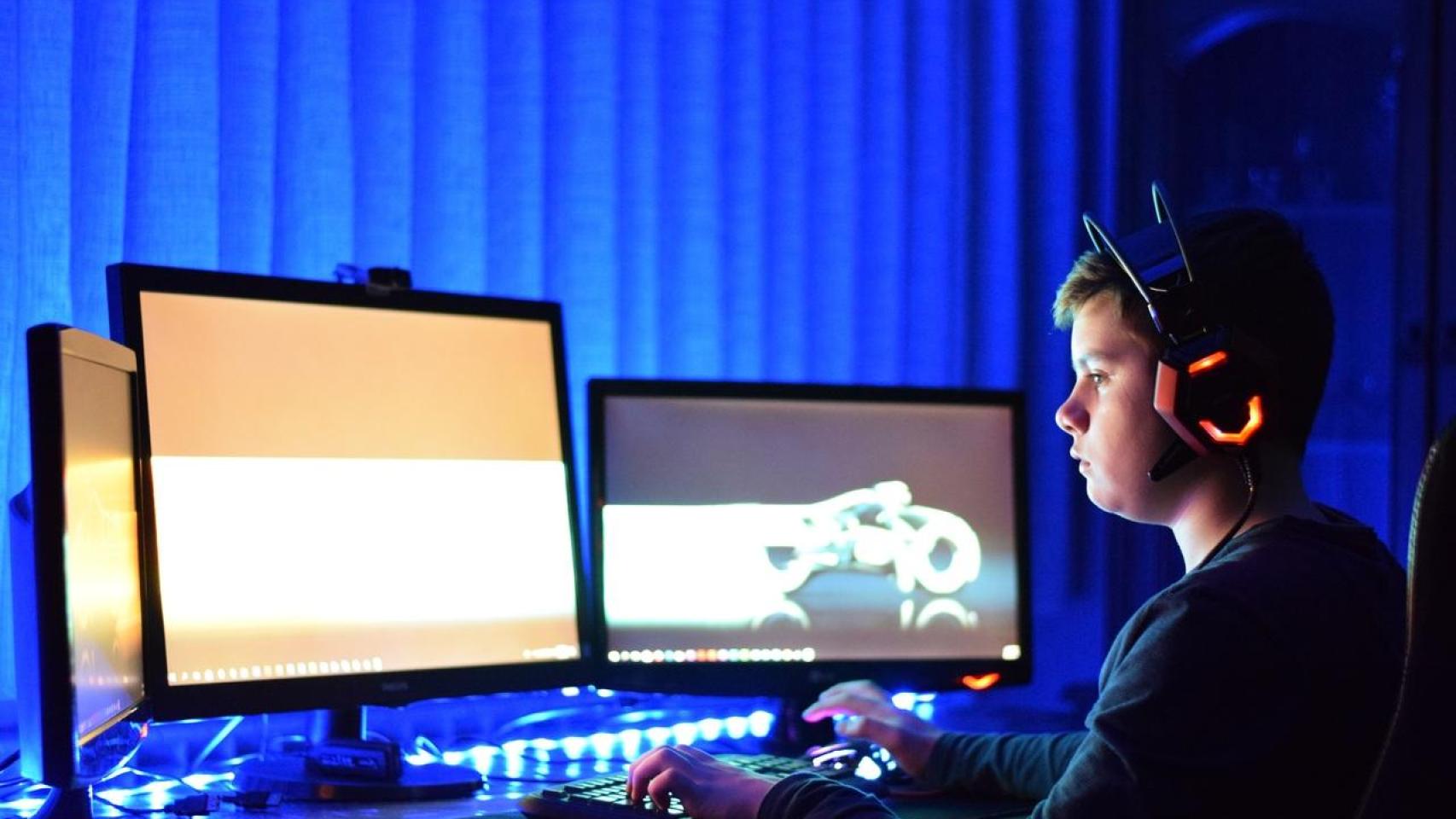 Joven gamer en su casa ante dos monitores