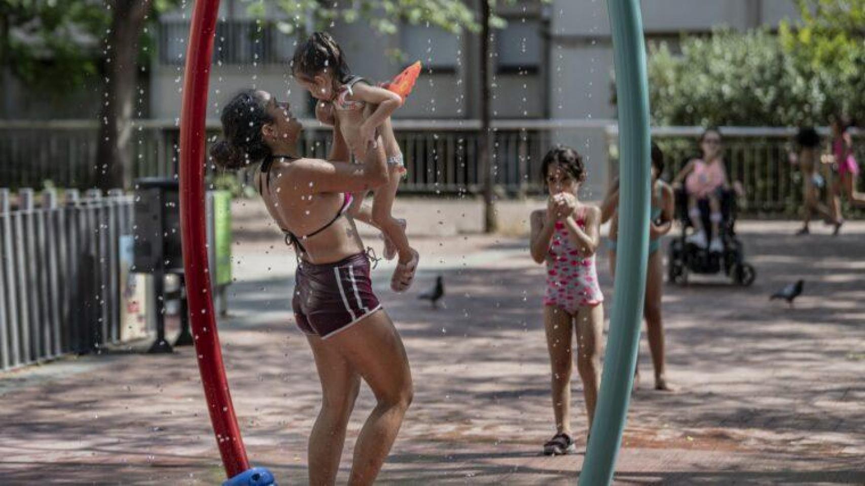 Personas jugando bajo una de las fuentes en Barcelona en una imagen de archivo 
