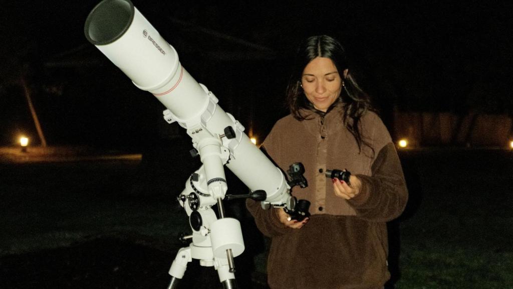 Una chica junto a un telescopio para ver un eclipse