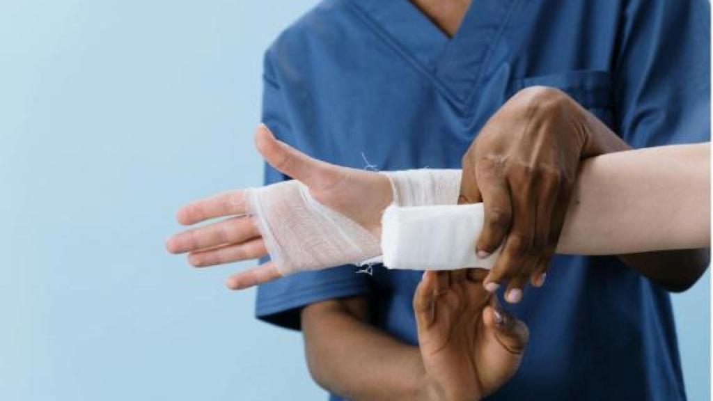 Un enfermero aplica un vendaje en una mano