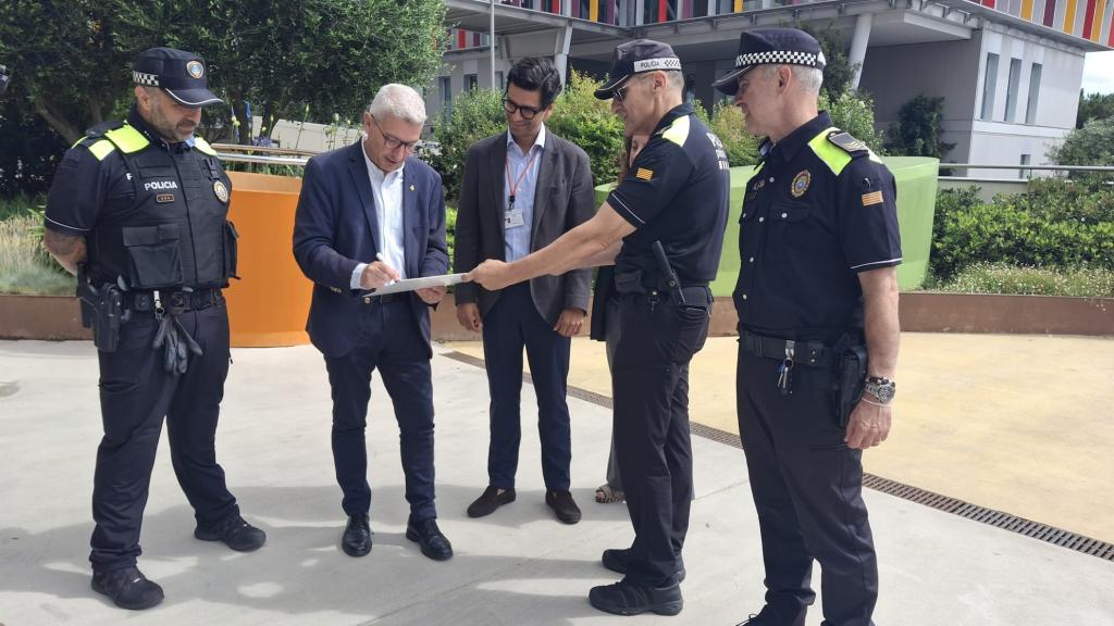 El alcalde de Esplugues, Eduard Sanz, y el director asistencial del SJD Pediatric Cancer Center Barcelona, junto a agentes de la Policía Local en el acto de entrega del cheque